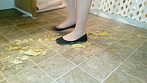 Suzi walks over unpeeled bananas, on floor, wearing her black ballet flats